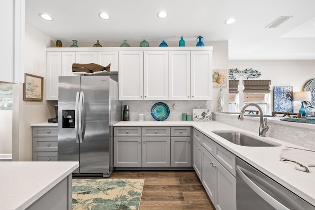 kitchen featuring appliances with stainless steel finishes, light countertops, a sink, and gray cabinetry