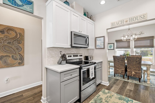 kitchen with dark wood-style floors, stainless steel appliances, light countertops, backsplash, and a chandelier