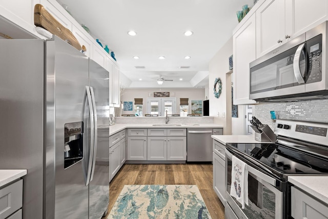 kitchen featuring stainless steel appliances, a sink, light wood-style floors, light countertops, and decorative backsplash