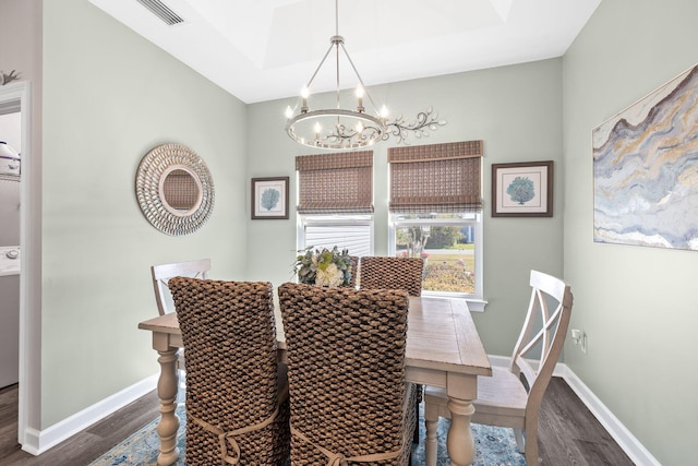 dining room with baseboards, visible vents, a chandelier, and wood finished floors