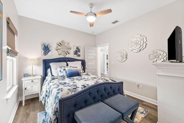 bedroom featuring a ceiling fan, visible vents, baseboards, and wood finished floors