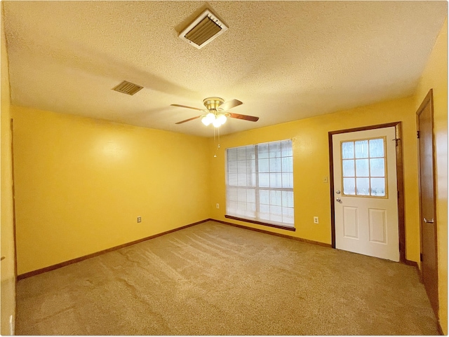 carpeted spare room with a ceiling fan, baseboards, visible vents, and a textured ceiling