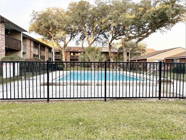 community pool with fence and a lawn