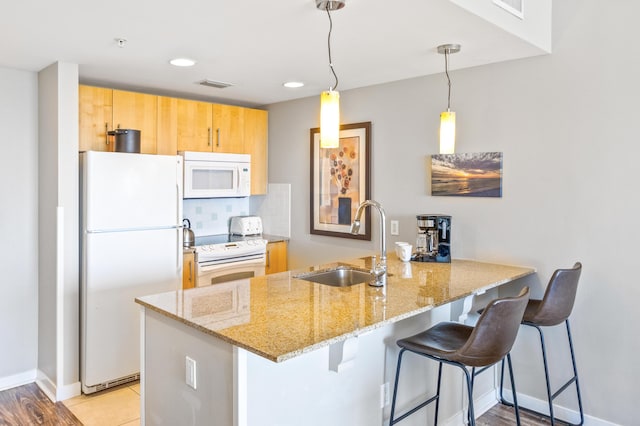 kitchen with tasteful backsplash, visible vents, a peninsula, white appliances, and a sink