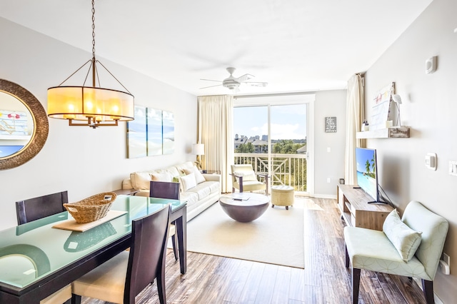 living area with ceiling fan with notable chandelier and wood finished floors