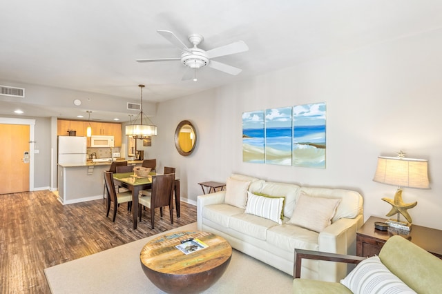 living area featuring visible vents, baseboards, a ceiling fan, and dark wood-style flooring