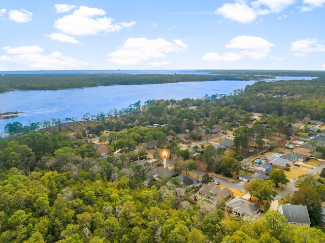 drone / aerial view featuring a water view, a wooded view, and a residential view