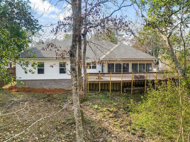 back of house featuring a deck, brick siding, roof with shingles, and a sunroom