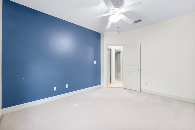 carpeted spare room featuring baseboards, visible vents, and a ceiling fan