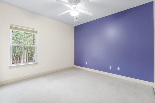 carpeted spare room featuring ceiling fan and baseboards