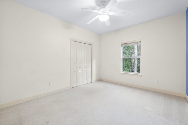 carpeted empty room featuring ceiling fan and baseboards