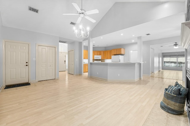 unfurnished living room featuring high vaulted ceiling, ceiling fan with notable chandelier, visible vents, baseboards, and light wood-style floors