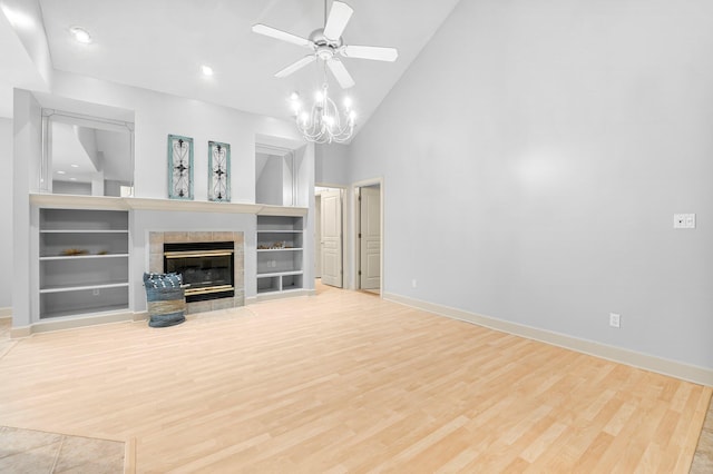 unfurnished living room with built in shelves, a fireplace, baseboards, and wood finished floors