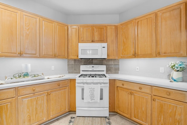 kitchen featuring light tile patterned floors, light countertops, white appliances, and tasteful backsplash