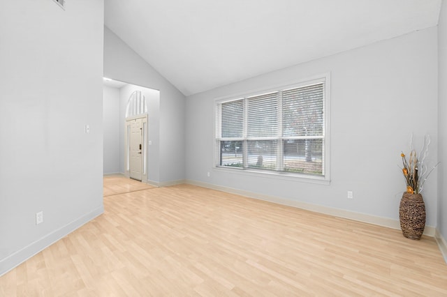 empty room featuring vaulted ceiling, light wood-style flooring, and baseboards