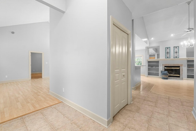 hallway with high vaulted ceiling, recessed lighting, wood finished floors, baseboards, and an inviting chandelier