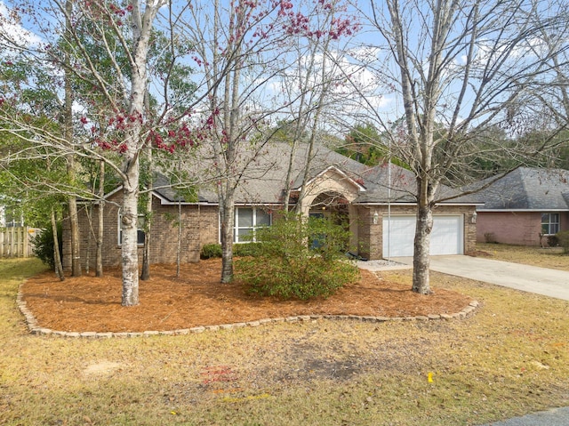 ranch-style home with a garage, brick siding, driveway, and fence