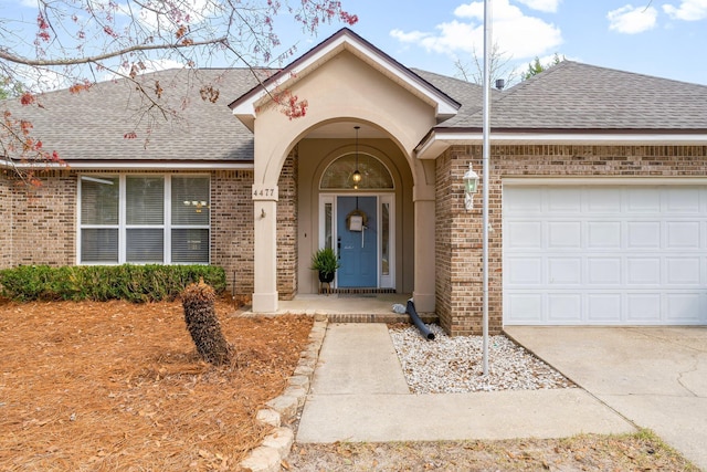 doorway to property with brick siding, roof with shingles, and an attached garage