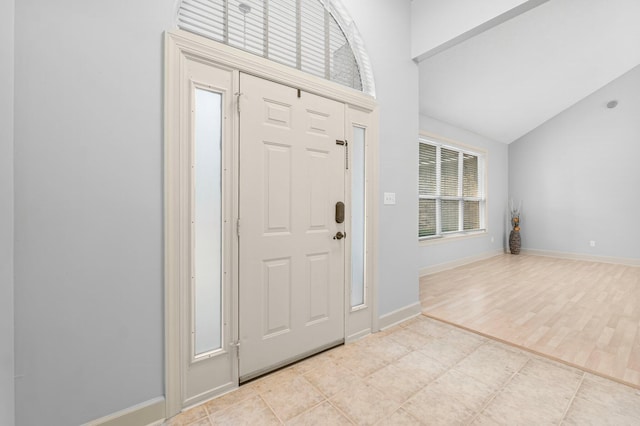 entryway featuring lofted ceiling, light wood-style flooring, and baseboards