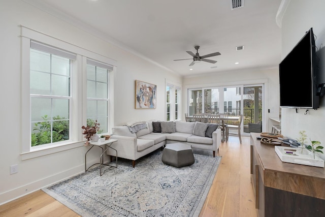 living room featuring visible vents, ornamental molding, light wood-style flooring, and baseboards