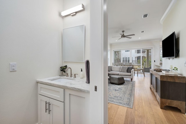 bathroom featuring two vanities, visible vents, a sink, and wood finished floors