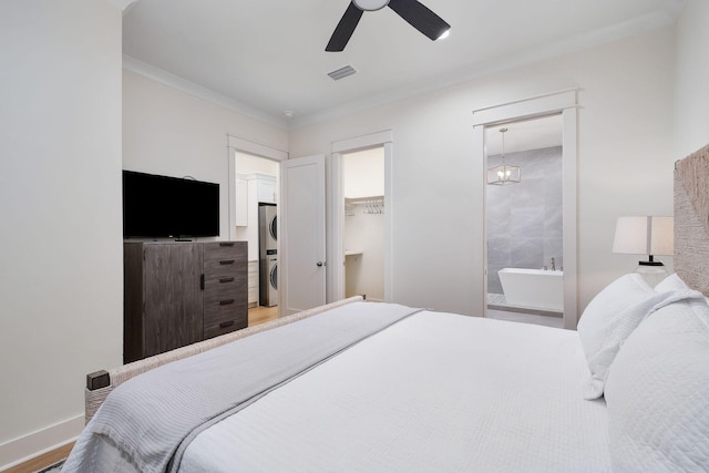 bedroom featuring crown molding, stacked washer and dryer, visible vents, a spacious closet, and wood finished floors