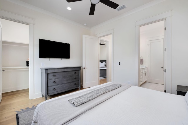 bedroom featuring visible vents, a spacious closet, crown molding, light wood-type flooring, and a closet