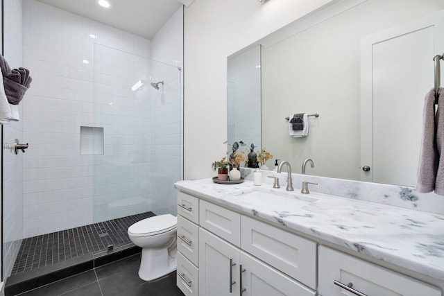 bathroom featuring vanity, tiled shower, tile patterned flooring, and toilet