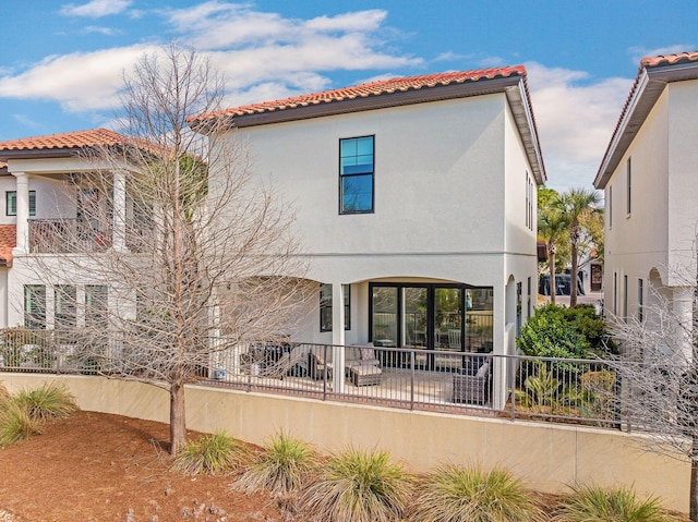 rear view of property with a tile roof and stucco siding