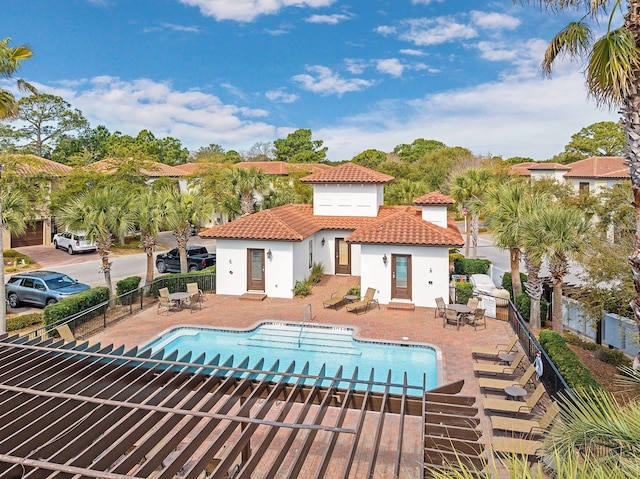 back of property featuring stucco siding, a patio area, fence, a community pool, and a tiled roof