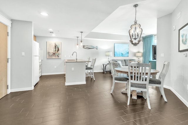 dining area with dark wood-style flooring, a notable chandelier, and baseboards