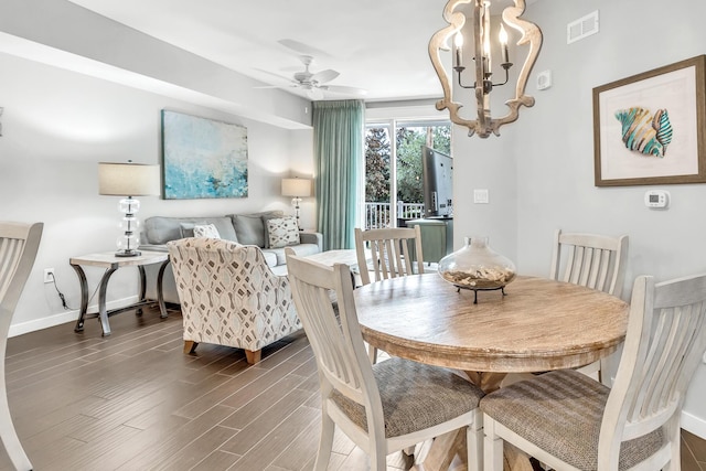 dining area featuring visible vents, dark wood finished floors, baseboards, and ceiling fan with notable chandelier