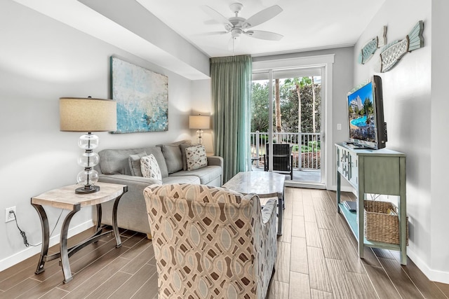 living area with baseboards, a ceiling fan, and wood tiled floor