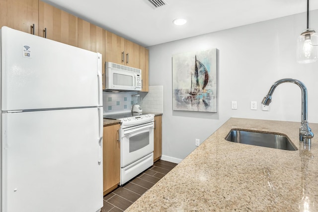 kitchen featuring light stone counters, white appliances, wood finish floors, a sink, and tasteful backsplash