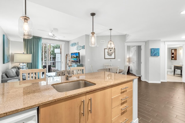 kitchen featuring light brown cabinets, a sink, open floor plan, dishwasher, and dark wood finished floors