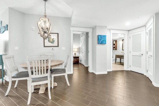 dining area featuring dark wood-style flooring, baseboards, and an inviting chandelier