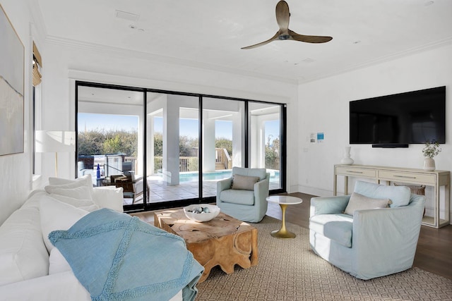 living area featuring ceiling fan, baseboards, wood finished floors, and crown molding