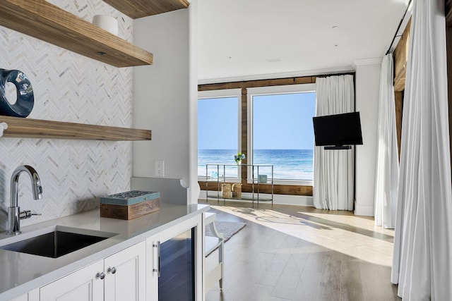 kitchen with wine cooler, a sink, white cabinetry, decorative backsplash, and open shelves