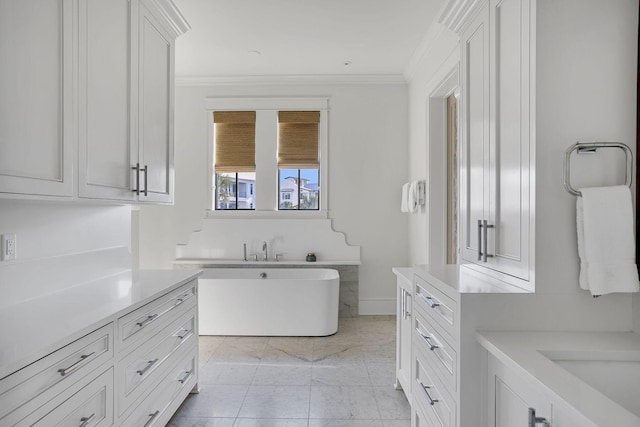 full bath with vanity, baseboards, a freestanding bath, marble finish floor, and ornamental molding