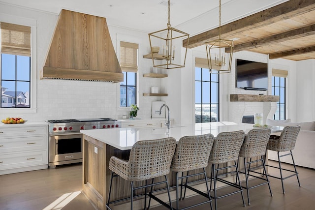 kitchen featuring beam ceiling, designer stove, light countertops, backsplash, and premium range hood