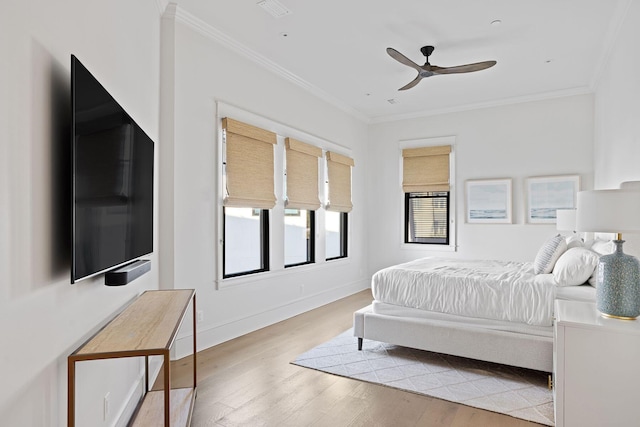 bedroom with a ceiling fan, baseboards, crown molding, and wood finished floors