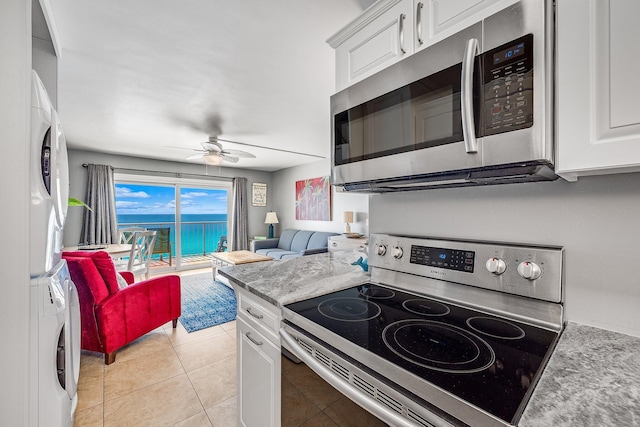 kitchen with ceiling fan, stainless steel appliances, stacked washer and clothes dryer, and white cabinetry