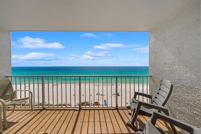 balcony with a water view and a view of the beach