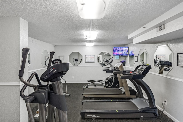 workout area with a textured ceiling, a textured wall, visible vents, and baseboards