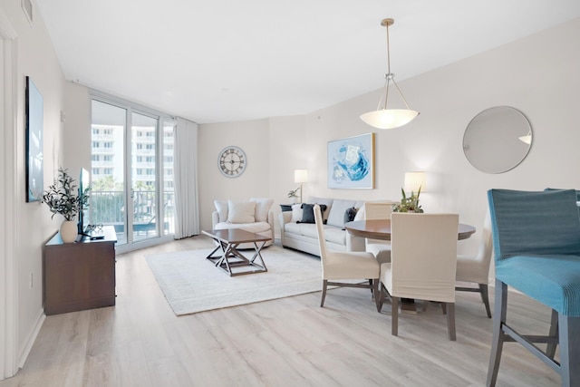 dining room featuring visible vents, baseboards, a wall of windows, and wood finished floors