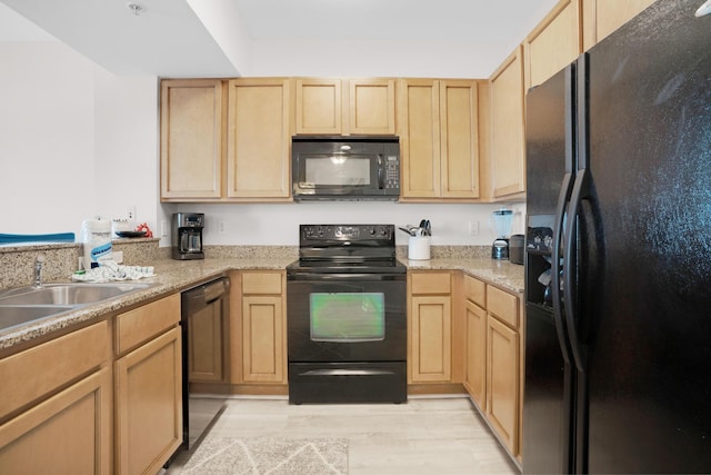 kitchen with black appliances, light brown cabinetry, a sink, and light wood-style flooring