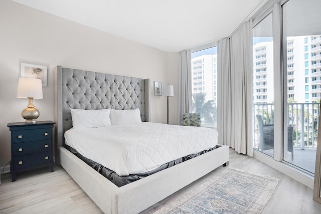 bedroom featuring light wood finished floors, access to outside, and floor to ceiling windows