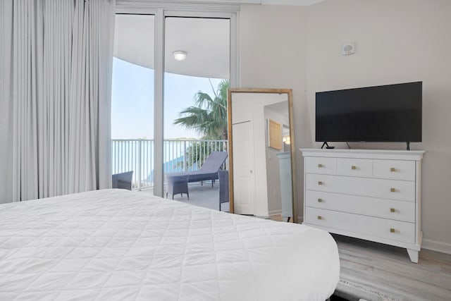 bedroom featuring baseboards, wood finished floors, and access to exterior