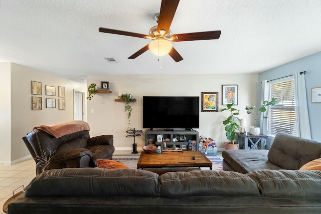 living room with tile patterned floors, visible vents, a textured ceiling, baseboards, and ceiling fan