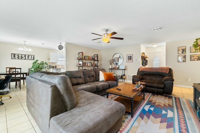 living room featuring light tile patterned floors, visible vents, a textured ceiling, and ceiling fan with notable chandelier